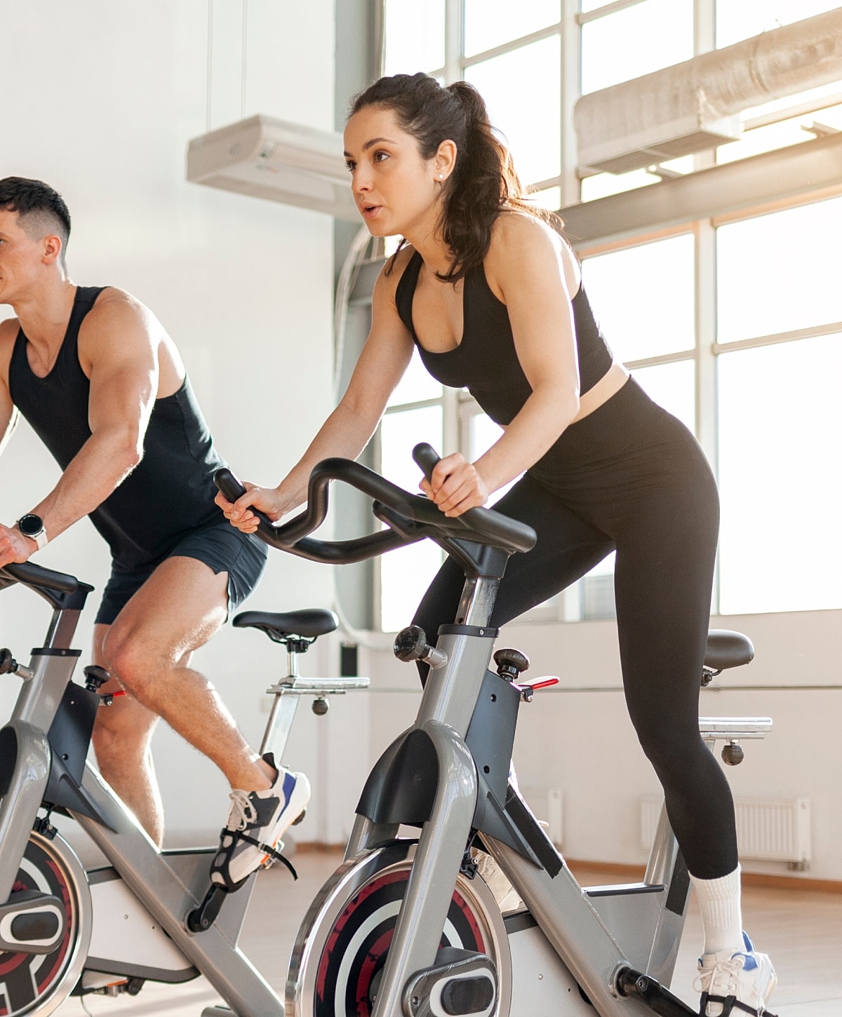 Couple exercising on stationary bikes indoors.